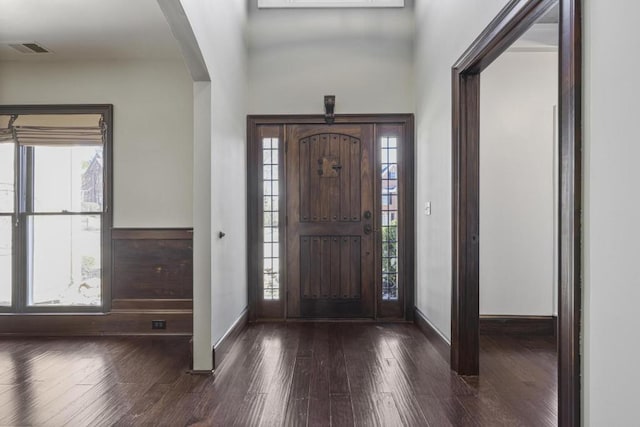 foyer featuring visible vents, arched walkways, baseboards, and wood finished floors