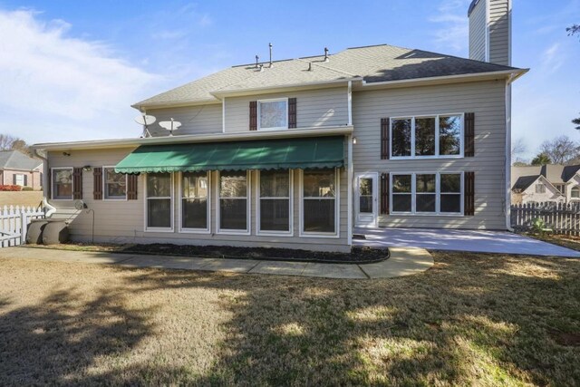 rear view of property with a patio area, fence, a lawn, and a chimney