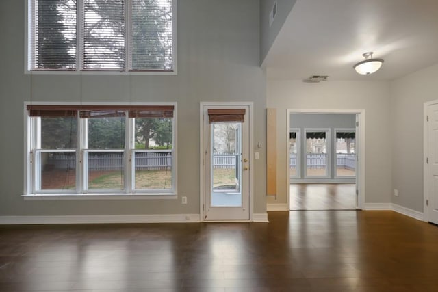 interior space featuring visible vents, wood finished floors, baseboards, and a towering ceiling