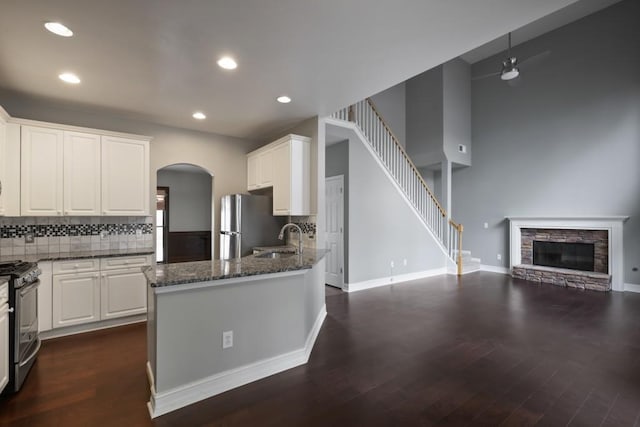 kitchen with open floor plan, dark stone countertops, appliances with stainless steel finishes, white cabinets, and a sink