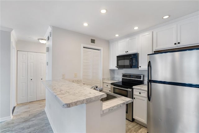 kitchen featuring stainless steel appliances, light countertops, visible vents, white cabinetry, and a sink