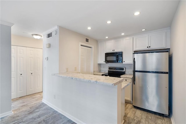 kitchen with light wood-style flooring, a peninsula, visible vents, white cabinets, and appliances with stainless steel finishes