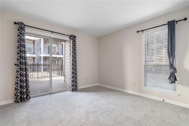 carpeted empty room featuring baseboards