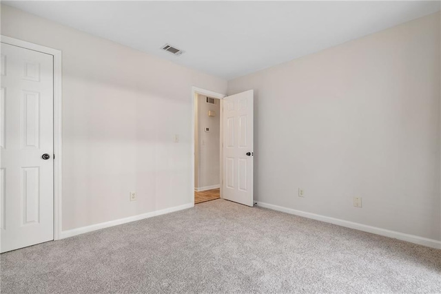 carpeted empty room featuring visible vents and baseboards