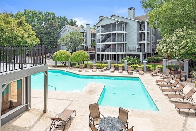 community pool with a patio area and fence