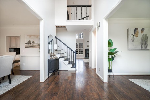 foyer entrance with a towering ceiling, stairs, dark wood finished floors, and crown molding