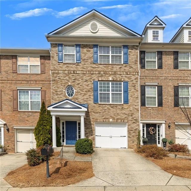 multi unit property featuring a garage, brick siding, and driveway