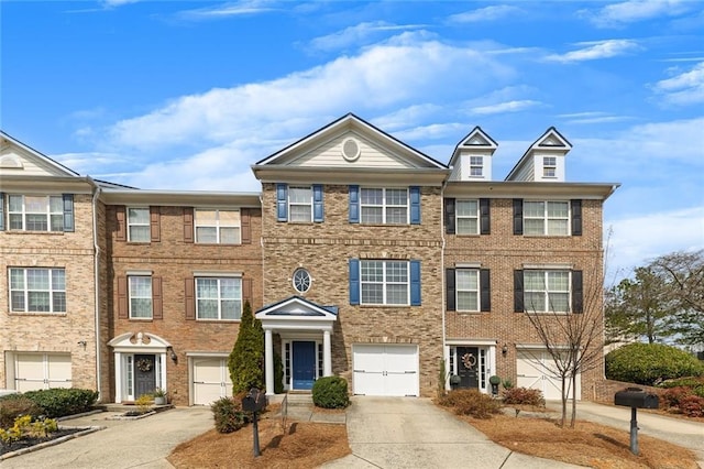 townhome / multi-family property featuring concrete driveway, an attached garage, and brick siding