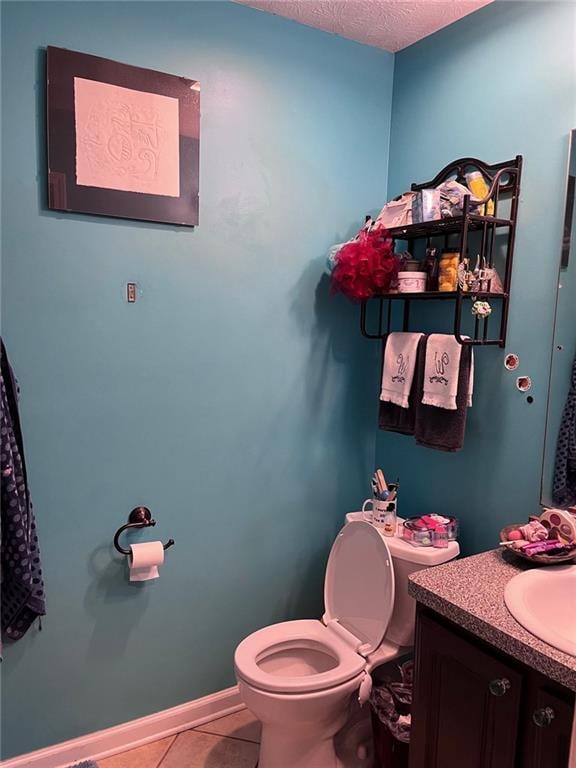 half bathroom with baseboards, toilet, vanity, tile patterned floors, and a textured ceiling