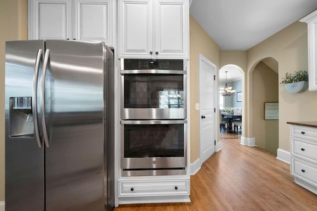 7251 Bluewater Ln, Douglasville, GA 30135 - kitchen with stainless steel appliances, light wood-style floors, white cabinets, baseboards, and a chandelier