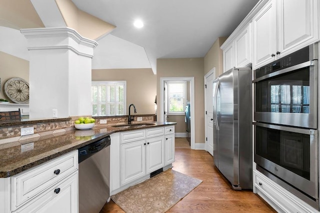 7251 Bluewater Ln, Douglasville, GA 30135 - kitchen with appliances with stainless steel finishes, a sink, white cabinets, light wood-type flooring, and dark stone counters