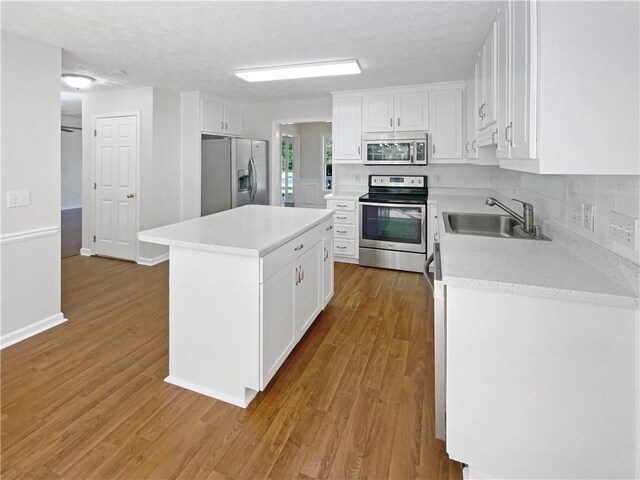 kitchen featuring light hardwood / wood-style flooring, white cabinets, a center island, stainless steel appliances, and sink