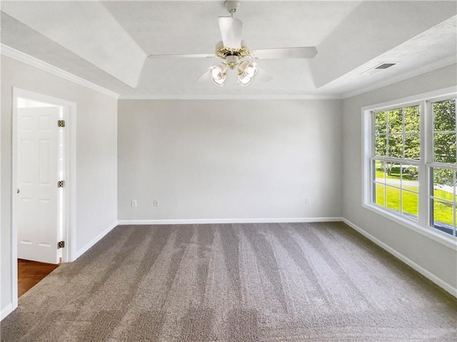 empty room featuring crown molding, a tray ceiling, ceiling fan, and dark colored carpet