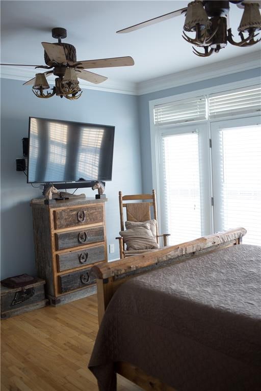 bedroom with hardwood / wood-style floors, ceiling fan, crown molding, and multiple windows