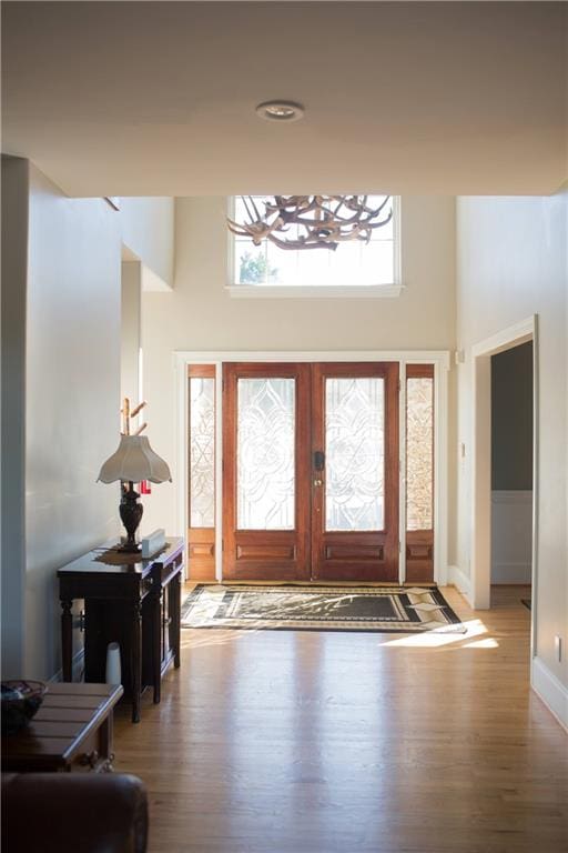 entryway featuring french doors, wood-type flooring, and a high ceiling