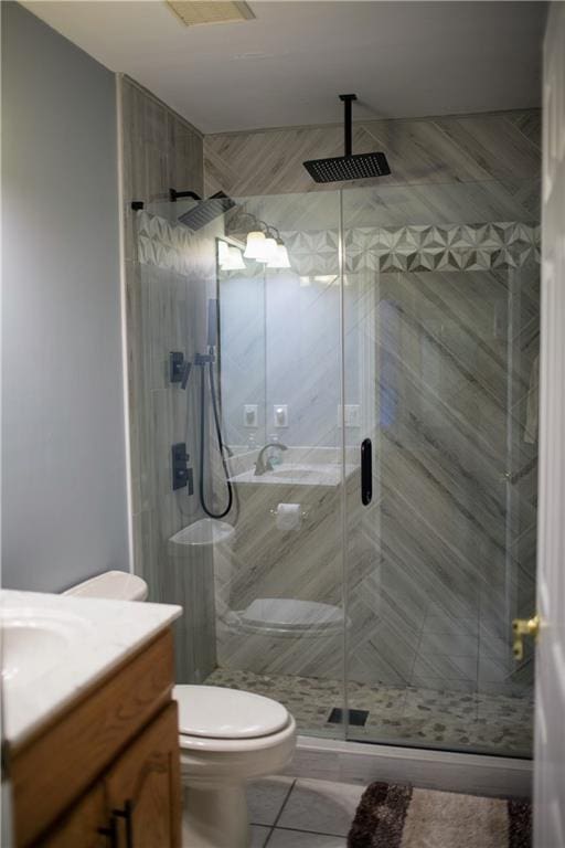 bathroom with tile patterned flooring, vanity, a shower with shower door, and toilet