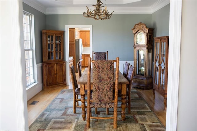 dining room featuring hardwood / wood-style floors, a healthy amount of sunlight, and crown molding