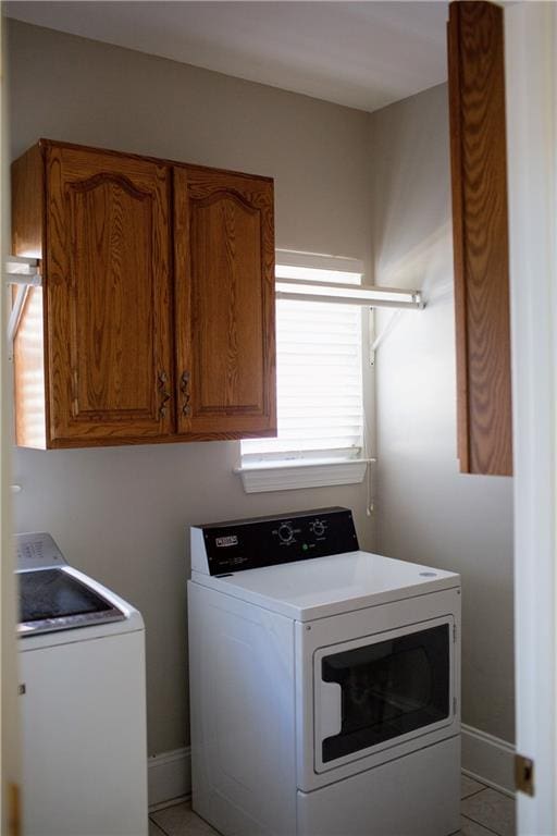 washroom with cabinets, washing machine and dryer, and light tile patterned floors