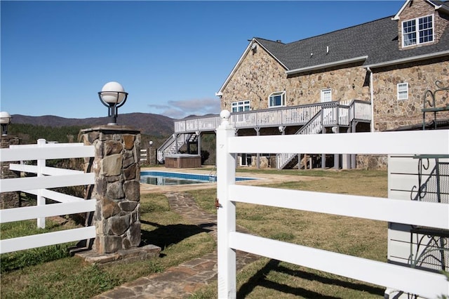 view of gate with a lawn and a swimming pool side deck with mountain view