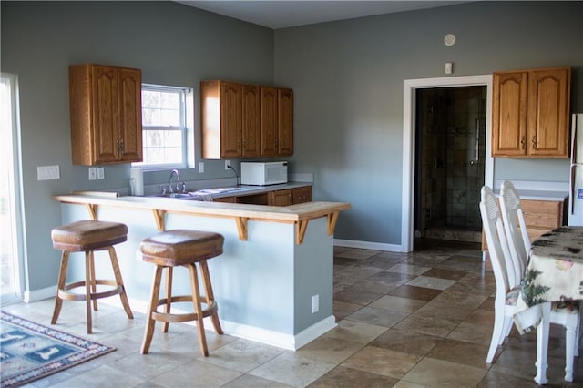 kitchen with a kitchen bar, kitchen peninsula, sink, and fridge