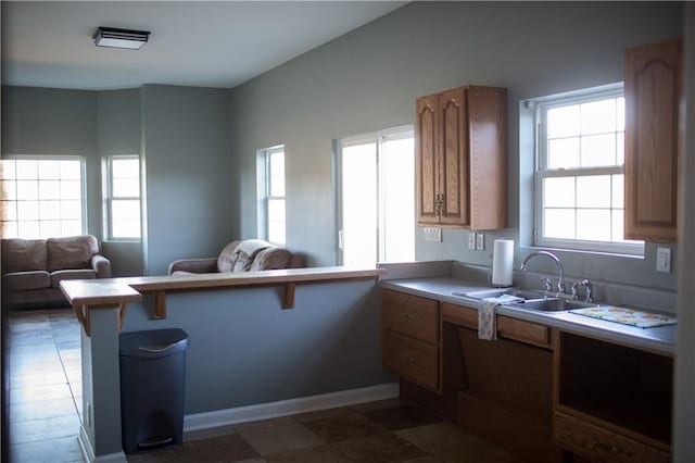 kitchen with a breakfast bar, kitchen peninsula, a wealth of natural light, and sink