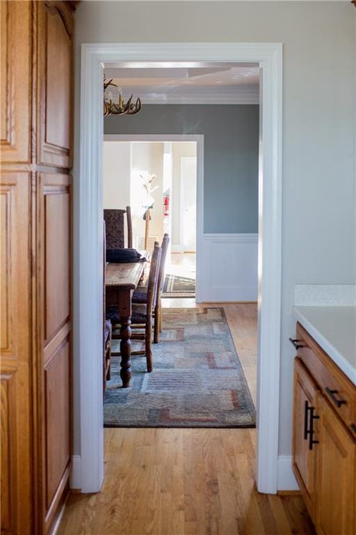 dining space with crown molding, light hardwood / wood-style floors, and an inviting chandelier