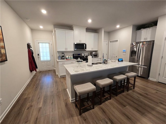 1702 Villageside Ct, Lawrenceville, GA 30043 - kitchen with appliances with stainless steel finishes, dark wood-style floors, a breakfast bar, decorative backsplash, and white cabinets