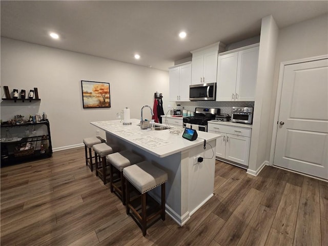 1702 Villageside Ct, Lawrenceville, GA 30043 - kitchen with appliances with stainless steel finishes, a sink, a breakfast bar, dark wood finished floors, and a kitchen island with sink