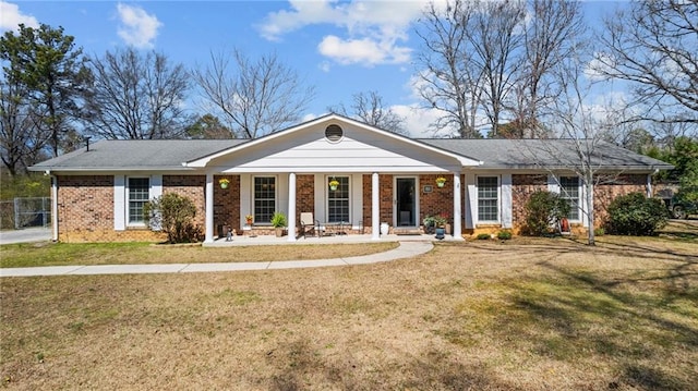 view of front facade with brick siding, covered porch, and a front yard