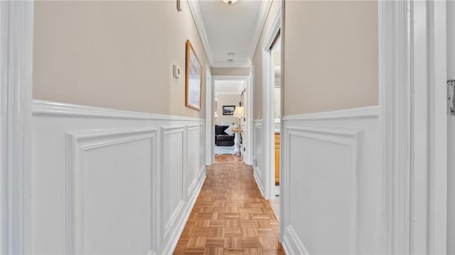 hallway featuring a decorative wall, a wainscoted wall, and ornamental molding