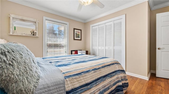 bedroom featuring a ceiling fan, wood finished floors, baseboards, a closet, and crown molding