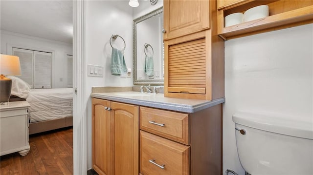 bathroom featuring vanity, crown molding, toilet, and wood finished floors