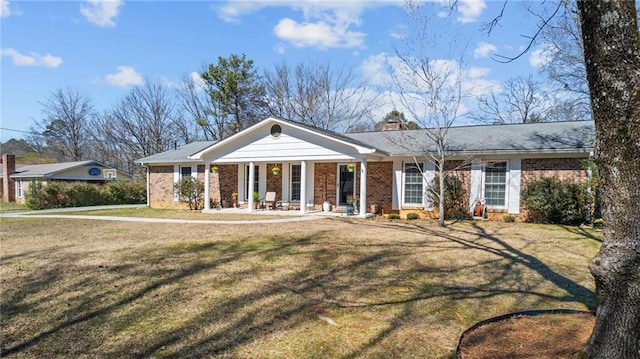 view of front facade featuring brick siding, a chimney, and a front yard