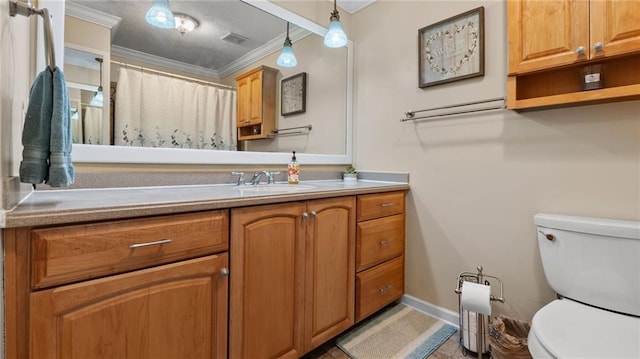 bathroom with vanity, toilet, crown molding, and baseboards