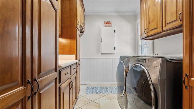 laundry area with crown molding, a wainscoted wall, light tile patterned floors, cabinet space, and separate washer and dryer