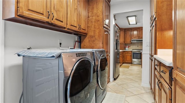 clothes washing area featuring cabinet space, light tile patterned floors, and washing machine and dryer