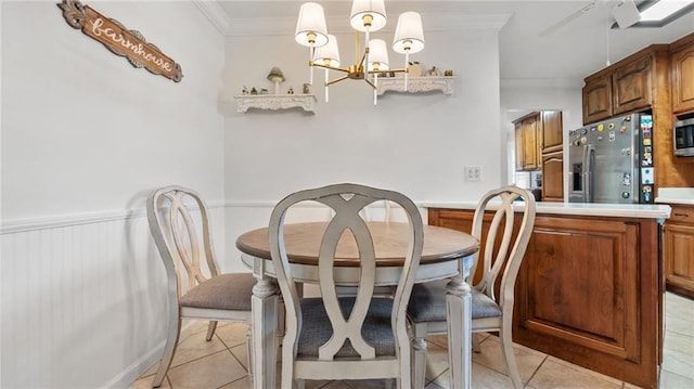 dining area with a chandelier, light tile patterned floors, wainscoting, and ornamental molding