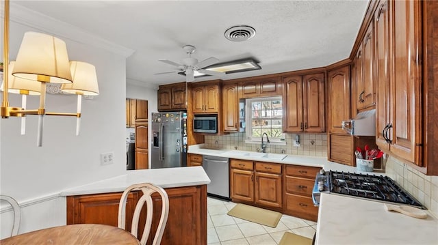 kitchen with visible vents, a sink, appliances with stainless steel finishes, brown cabinetry, and light countertops