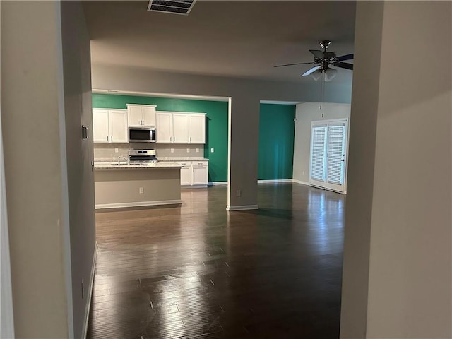 unfurnished living room featuring dark wood-type flooring and ceiling fan