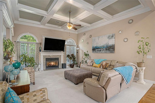 living room featuring coffered ceiling, baseboards, ceiling fan, a fireplace with flush hearth, and beam ceiling