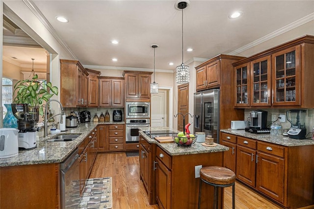 kitchen featuring a sink, brown cabinetry, stainless steel appliances, a kitchen island with sink, and light wood-style flooring