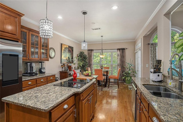 kitchen featuring black electric cooktop, light wood-style floors, glass insert cabinets, and brown cabinetry