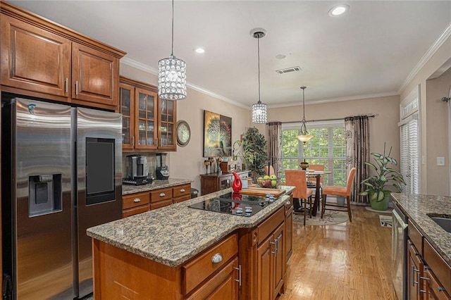 kitchen featuring light stone countertops, light wood-style flooring, visible vents, brown cabinets, and stainless steel appliances