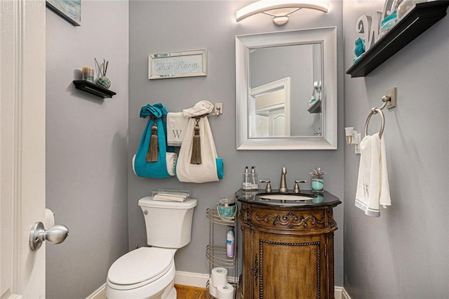 bathroom with toilet, baseboards, and vanity