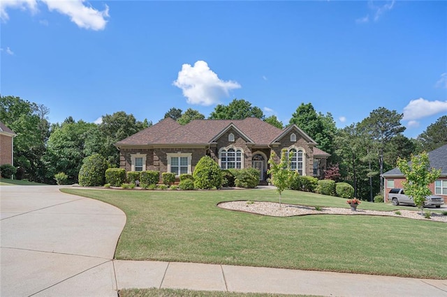 single story home featuring stone siding and a front yard