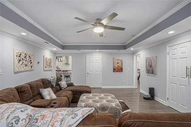 living area with a ceiling fan, ornamental molding, a tray ceiling, and wood finished floors