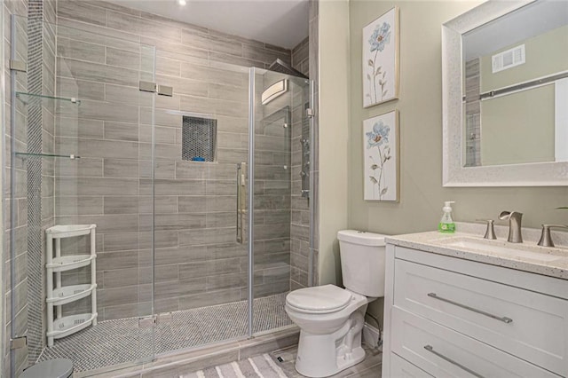 full bathroom featuring vanity, toilet, visible vents, and a stall shower