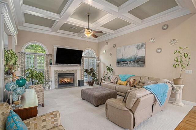 living room featuring coffered ceiling, baseboards, ceiling fan, a fireplace with flush hearth, and beam ceiling