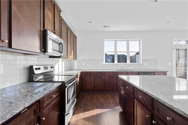 kitchen featuring plenty of natural light, light stone countertops, appliances with stainless steel finishes, and sink