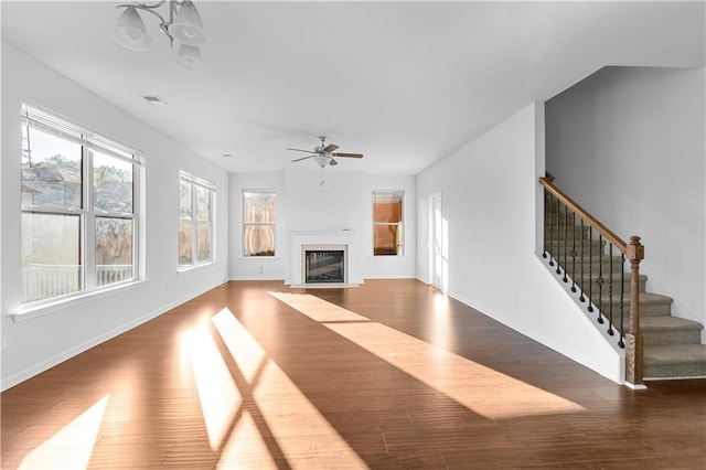 unfurnished living room featuring ceiling fan with notable chandelier and wood-type flooring